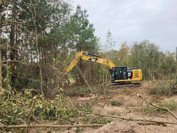 CAT excavator clearing wooded site with trees and brush removal
